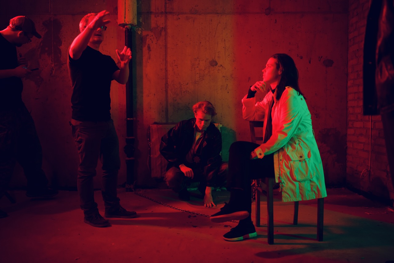 The director blocking a scene with two actors under red light.