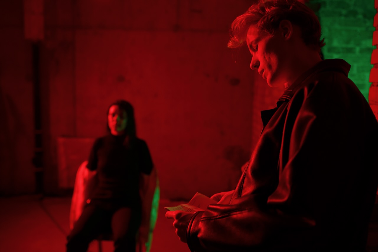 An actor reading sides, another seated in the background.