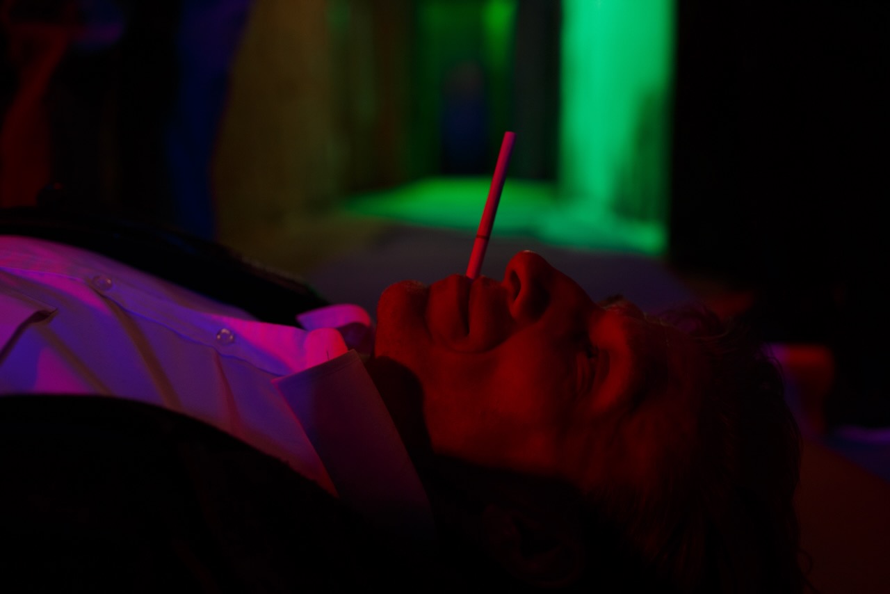 A man lying back with a cigarette standing on his lip.